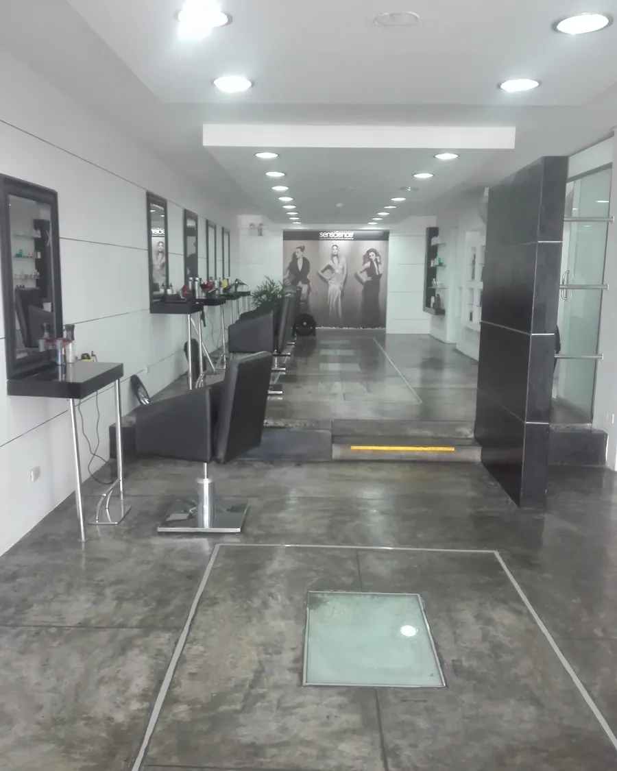 Interior de Mac Salón & Spa: piso de cemento pulido, espejos y sillas negras